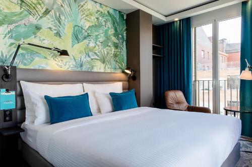 a bedroom with a large white bed with blue pillows at Motel One Barcelona-Ciutadella in Barcelona