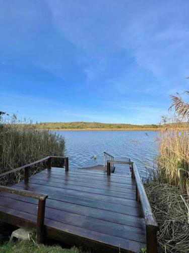 a wooden dock sitting on the side of a lake at Living The Breede-Wooden House in Malgas