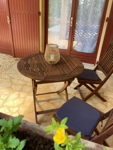 a wooden table and a chair on a patio at Les Eaux Vives in Manaurie