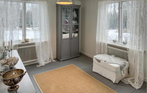 a living room with a chair and a cabinet and windows at 4 Bedroom Stunning Home In Närkesberg in Närkesberg