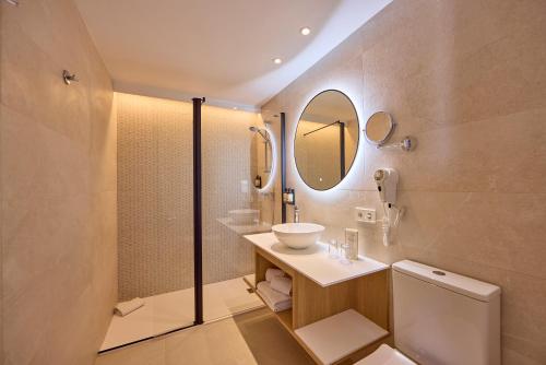 łazienka z umywalką, toaletą i lustrem w obiekcie Universal Hotel Bikini w Cala Millor