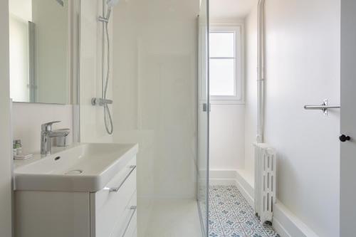 une salle de bain blanche avec un lavabo et une douche dans l'établissement The Paris 15 Place, à Paris