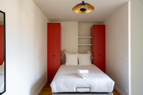 une chambre avec des portes rouges et un lit blanc dans l'établissement The Paris 15 Place, à Paris