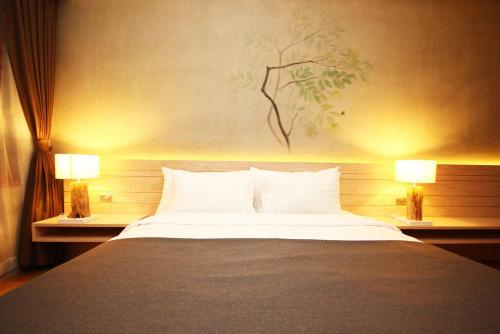 a bedroom with a large bed with two lamps at Chu Hotel in Chiang Mai