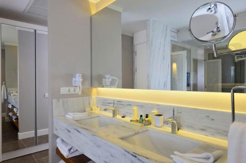 baño con lavabo y espejo grande en Sundance Suites Hotel, en Turgutreis
