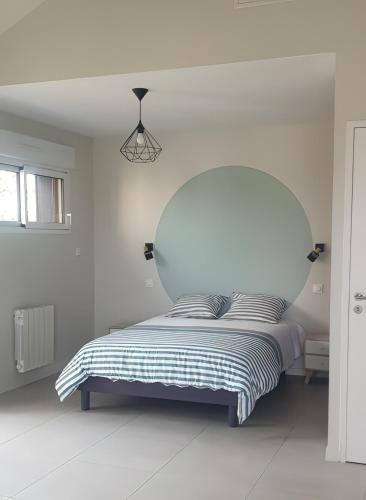 une chambre blanche avec un lit avec une tête de lit en verre dans l'établissement Studio Pic au vert, à Martigné-Ferchaud