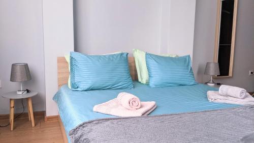 Una cama con almohadas azules y toallas rosas. en Lux 1 Apartment with Free Parking, en Plovdiv