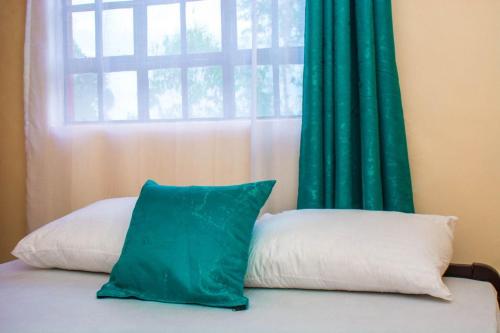 a window with a green curtain and a pillow on a bed at Eagles one bedroom in Kisii CBD with Balcony in Kisii