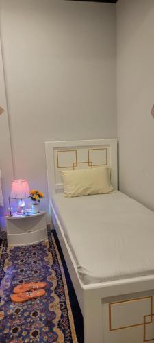 a white bed in a room with a rug and a table at Home Away Apartment in Abu Dhabi