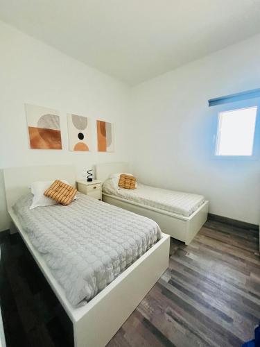 two beds in a room with white walls and wooden floors at Villa Alegría Gran Canaria Piscina Climatizada in Las Palmas de Gran Canaria