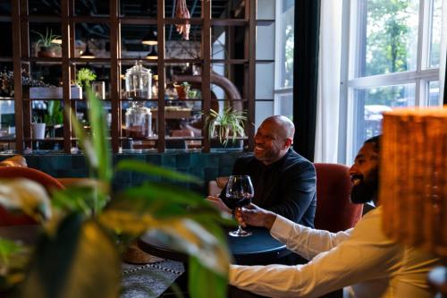two men sitting at a table with a glass of wine at Hotel Nell - Union Market in Washington