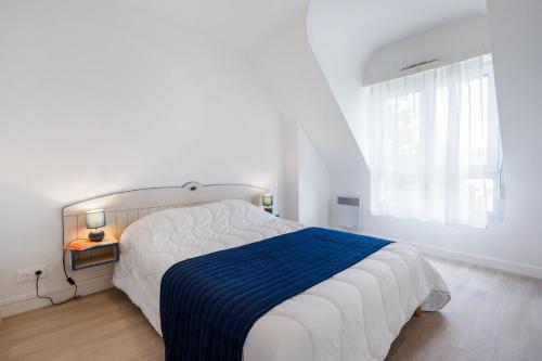 um quarto branco com uma cama grande e um cobertor azul em Résidence Pierre & Vacances La Voile d'Or em Ile aux Moines