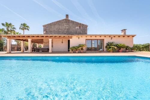 a villa with a swimming pool in front of a house at Can Xuri in Campos