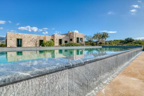 an infinity pool in front of a stone house at Villa Sand and Stone in Aliki