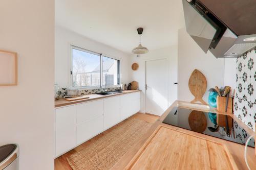 a kitchen with white cabinets and a window at Maison neuve pour 8 - 500m plage du Rouvran in Le Tour-du-Parc
