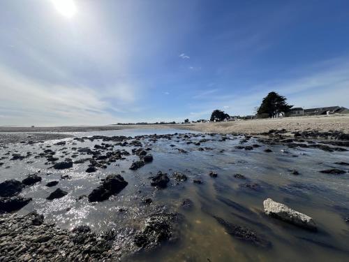 a beach with rocks and the sun in the sky at Maison neuve pour 8 - 500m plage du Rouvran in Le Tour-du-Parc
