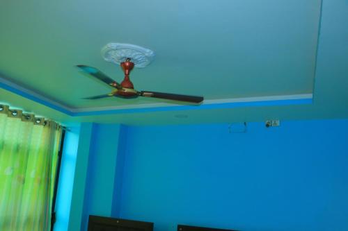 a ceiling fan in a room with a blue ceiling at Hotel Diamond in Bharatpur