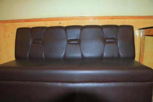 a brown leather couch sitting in a room at Hotel Diamond in Bharatpur
