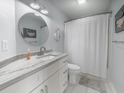 a bathroom with a sink and a toilet and a mirror at Beach Please in Surf City