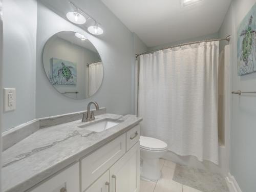 a white bathroom with a sink and a mirror at Beach Please in Surf City