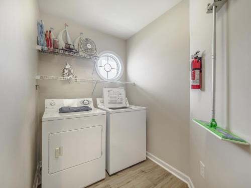 a laundry room with a washer and dryer and a clock at Beach Please in Surf City