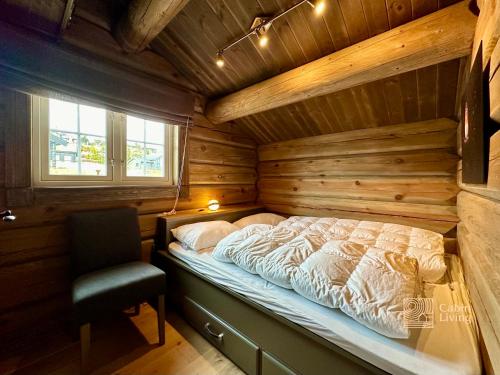 a bed in a wooden room with a chair in a cabin at Newer lovely cabin in Birkebeinerbakken Sjusjøen in Ringsaker