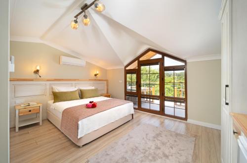 a bedroom with a bed and a large window at Orange Garden Hotel Akyaka in Akyaka