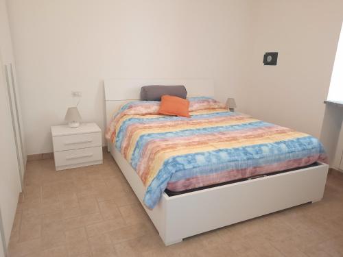 a white bedroom with a bed with a colorful comforter at Appartamento IL Tulipano in Brezzo
