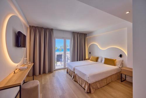 pokój hotelowy z łóżkiem i dużym oknem w obiekcie Universal Hotel Bikini w Cala Millor