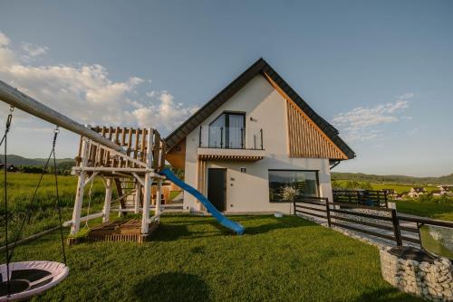 a house with a slide in front of it at To Je To apartamenty in Maniowy