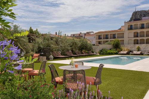 a garden with a table and chairs and a pool at Marconia Boutique Residence in L'Estartit