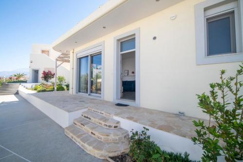Una casa blanca con unas escaleras delante. en Villa Kassandra, en Pitsidia