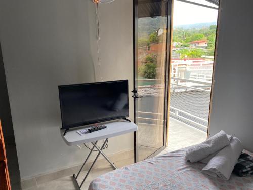 een slaapkamer met een flatscreen-tv en een bed bij Hotel Pacuare Turrialba in Turrialba