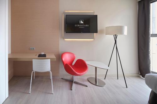 a living room with a red chair and a desk at Eurostars Don Cándido in Terrassa