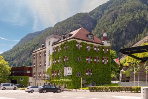 a building covered in ivy in front of a mountain at Hotel Sachsenklemme in Fortezza
