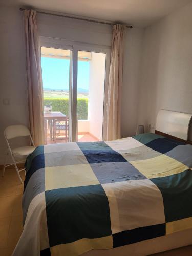 a bedroom with a bed and a window with a view at Luxury Ground Floor Apartment at Golf Resort Condado de Alhama with Private Garden & Pools in El Romero