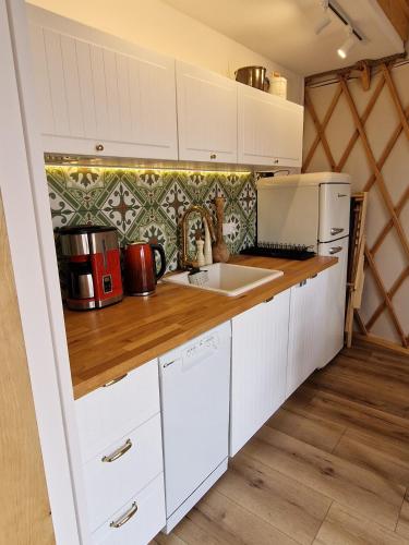 a kitchen with white cabinets and a counter top at Osada JurtCamp w Witowie in Witówko