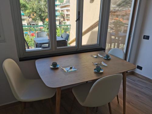 a wooden table and chairs with cups and saucers on it at VERDEACQUA Flat in Rapallo