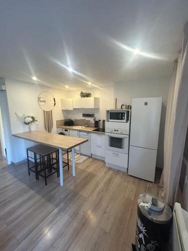 une cuisine avec une table et un réfrigérateur blanc dans l'établissement Appartement, à Marseille