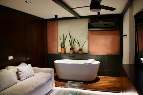a bathroom with a tub and a couch and plants at VILLA MERIDA BOUTIQUE HOTEL - Adults Only in Mérida