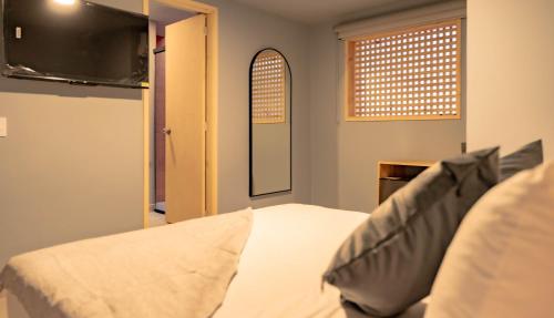 a bedroom with a bed and a mirror and a window at Leviu by Bernalo Hotels in Medellín