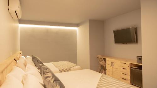 a bedroom with a bed and a tv on the wall at Leviu by Bernalo Hotels in Medellín