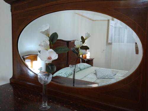 - un miroir dans une chambre avec un lit et un vase avec des fleurs dans l'établissement L'Orto di Sant'Andrea, à Pise