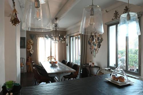 une salle à manger avec une table, des chaises et des fenêtres dans l'établissement Maison atypique proche Luberon et Avignon, à Châteauneuf-de-Gadagne