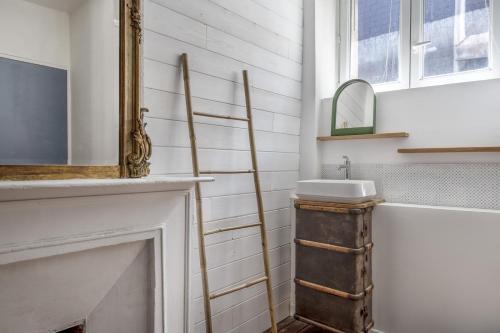 La salle de bains est pourvue d'un lavabo et d'un miroir à côté de la cheminée. dans l'établissement BOURSE - Appart ambiance bohème chic à Nantes, à Nantes