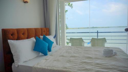 een slaapkamer met een groot bed met blauwe en witte kussens bij Dinuda Resort in Kalpitiya