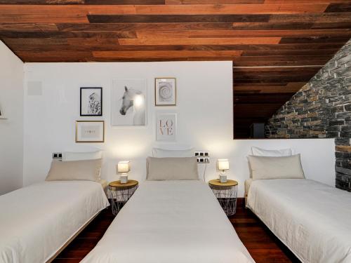 two beds in a room with wooden ceilings at Xauxa in Sant Pere de Vilamajor