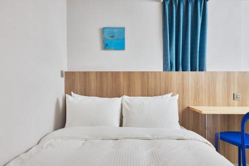 a bed in a hotel room with a blue chair at The Blue by Just Inn in Taipei