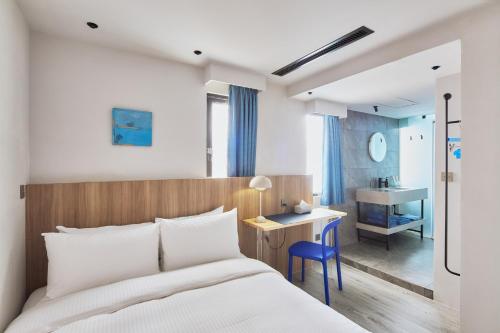 a bedroom with a bed and a desk and a sink at The Blue by Just Inn in Taipei