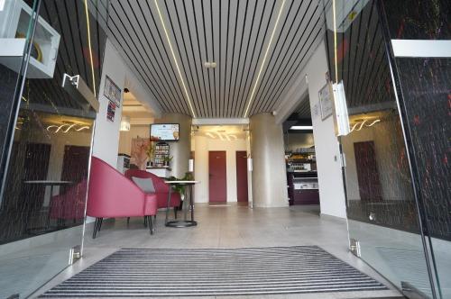 a lobby with a pink chair and a table at Anaïs Hôtel Bourges Nord Saint-Doulchard in Bourges